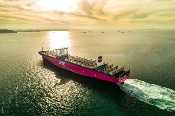 Cargo ship sailing under golden sunset.