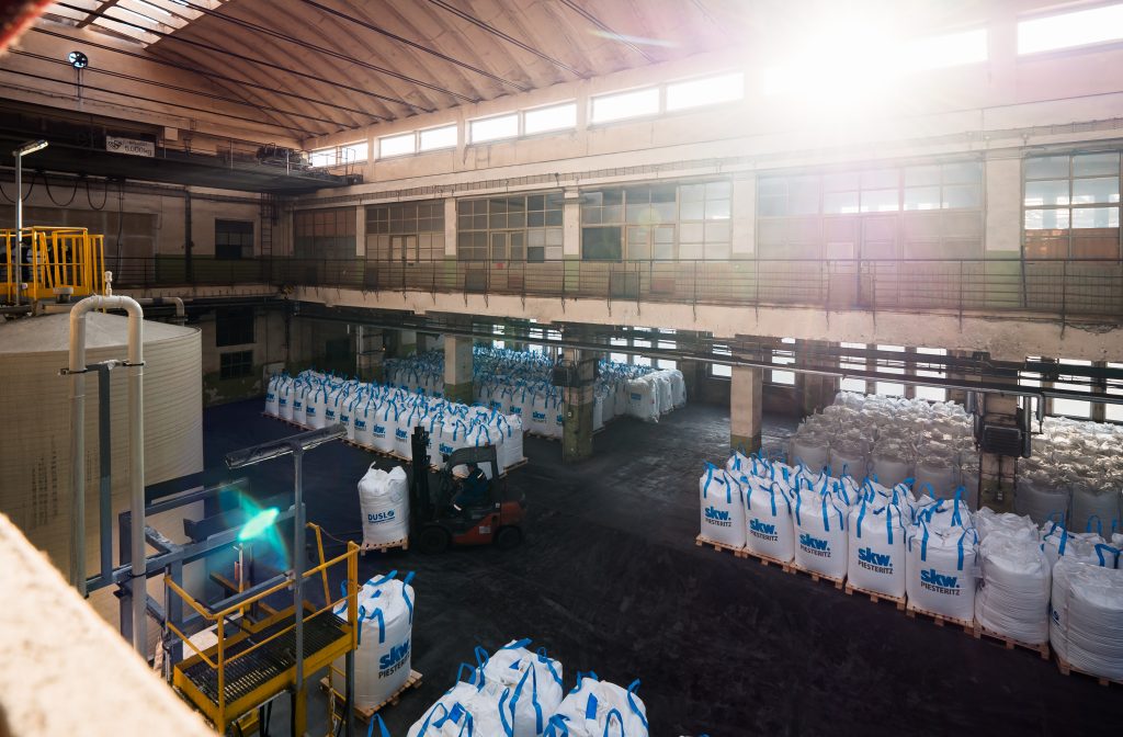 Warehouse with stacked industrial bulk bags and forklift.