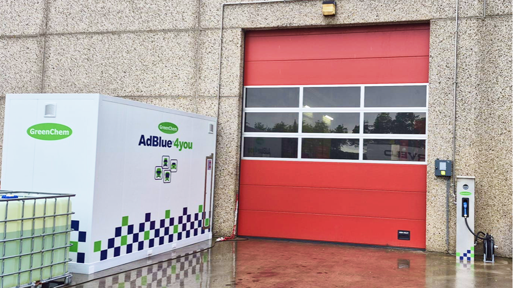 AdBlue-tank naast rode roldeur van loods