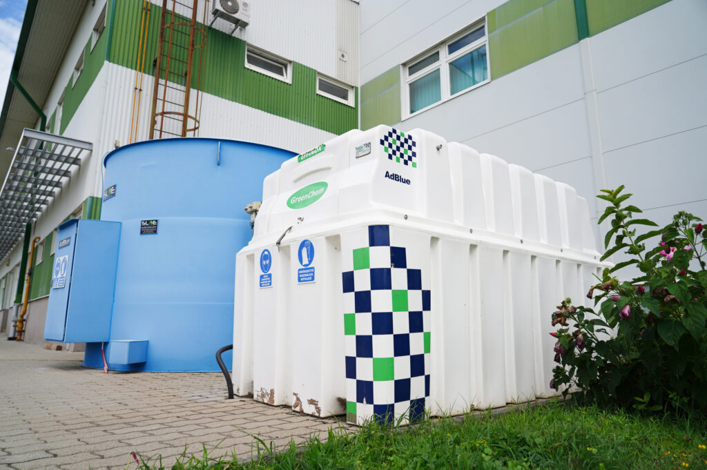 Chemical storage tanks outside a green-and-white industrial building